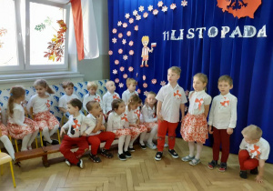 Dzieci grane na biało czerwono mówią wiersze na tle dekoracji święta 11 listopada