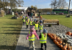 Dzieci spacerują w parach na terenie kompleksu wśród dekoracji z dyń