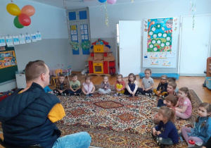 dzieci siedzą na dywanie i zadają pytania Panu Przemkowi