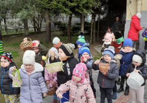 Dziecie stoją i pokazują koszyczki do których będą zbierać jajeczka