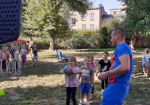 Dzieci wykonują kolejno zadanie - rzut piłką do kosza