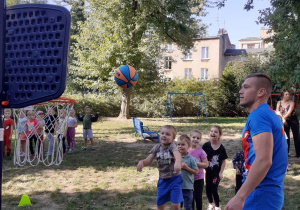 Dzieci wykonują kolejno zadanie - rzut piłką do kosza