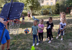 Dzieci wykonują kolejno zadanie - rzut piłką do kosza