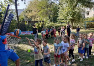 Dzieci wykonują kolejno zadanie - rzut piłką do kosza