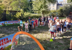 Dzieci kolejno wykonują zadania - rzut do bramki i strzał do bramki