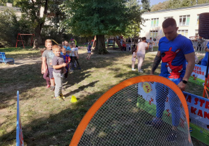 Dzieci kolejno wykonują zadania - rzut do bramki i strzał do bramki