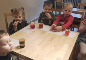 Dzieci siedzą przy stalikach i piją herbatkę.