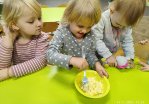 Dzieci siedż przy stoliczku, mieszają w miseczkach czosnek z masełkiem