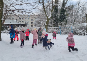 Dzieci biegają po śniegu w ogrodzie przedszkolnym