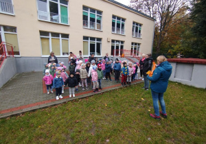 Dzieci ustawione grupami na tarasie słuchają zasad obowiązujących podczas zbierania ziemniaków w ogrodzie