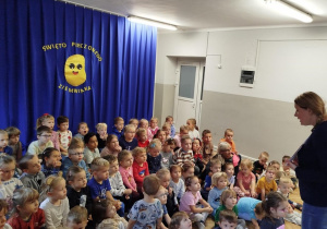 Dzieci siedzą i słuchają bajki o ziemniaku, w tle dekoracja na granatowym materiale