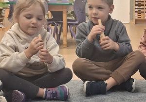 Dwoje dzieci siedzi w kole i oglądają pietruszkę