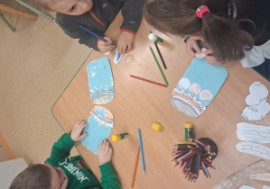 Dzieci wykonują prace plastyczne przy stoliku