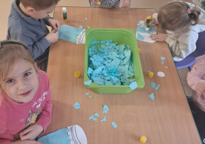 Dzieci wykonują prace plastyczne przy stoliku