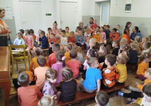 Nauczycielka opowiada dzieciom o ich pięknych kreatywnych dyniach, dzieci siedzą wokół i słuchają