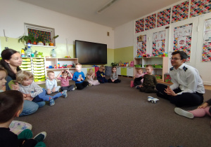 Dzieci siedzą na dywanie i słuchają opowiadań o samolotach, lotnisku i pracy pilota