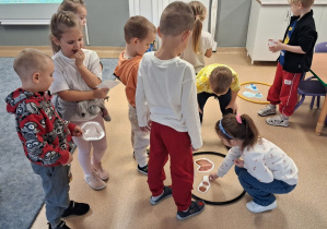 Dzieci segregują śmieci do odpowiednich kółek - koszy na śmieci