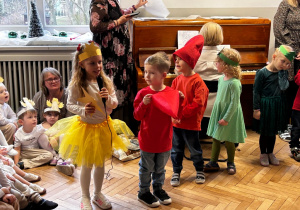 Dziewczynka w roli gwiazdeczki rozmawia z krasnalami i choinkami