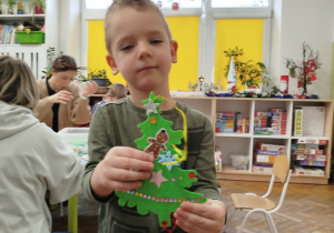 Chłopczyka pokazuje wykonaną przez siebie choinkę