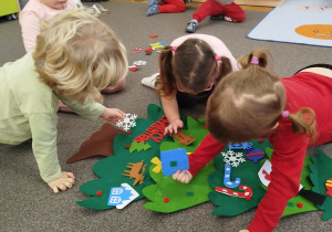 Dzieci przyczepiają elementy na rzepy do choinki