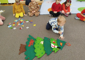 Chłopczyk przyczepia element na choinkę