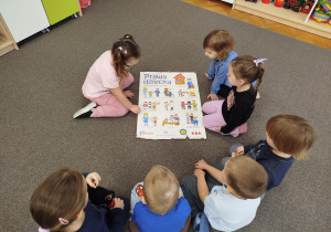 Dzieci oglądają planszę na dywanie o prawach dziecka