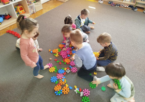 Dzieci szukają na dywanie odpowiedniego klocka w danym kolorze