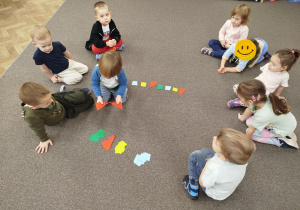 Chłopczyk układa czerwone trójkąty w odpowiednim miejscu na dywanie