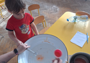 Dziecko trzyma klucz, nauczycielka leje wosk przez dziurkę