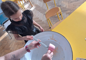 Dziecko trzyma klucz, nauczycielka leje wosk przez dziurkę