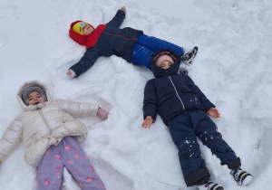 Dzieci robią aniołki na śniegu