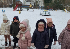 Dzieci stoją i słuchaja o zasadach bezpiecznej zabawy na śniegu