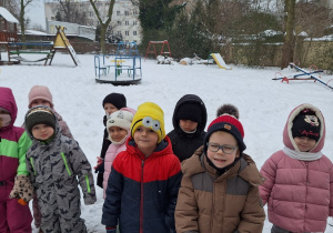Dzieci stoją i słuchaja o zasadach bezpiecznej zabawy na śniegu