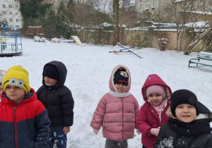 Dzieci stoją i słuchaja o zasadach bezpiecznej zabawy na śniegu